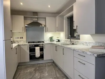 a kitchen with white cabinets and a stove top oven at Spring gardens in Lower Darwen