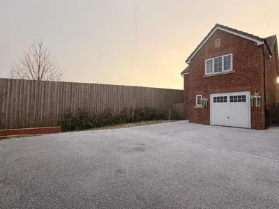 a red brick house with a white garage at Spring gardens in Lower Darwen