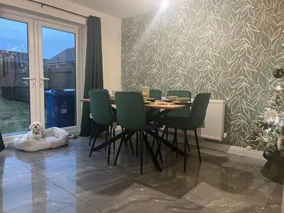 a dining room with a table and green chairs at Spring gardens in Lower Darwen