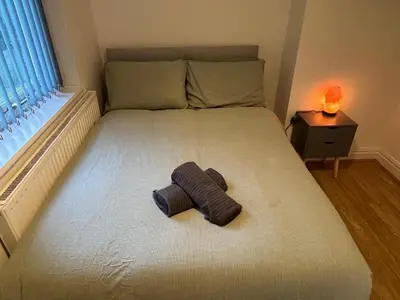 a large bed with a rolled up towel on it at 3BR Home, Parking, Families, Contractors, Wi-Fi in Liverpool