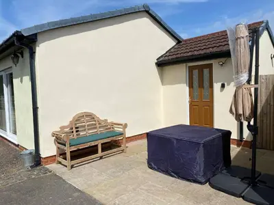 a bench sitting on a patio in front of a house at Charming Retreat with Sauna, Dog Swimming Pool, and Rural Charm in Leyland
