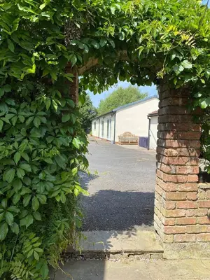 an archway of a brick building with a hedge at Charming Retreat with Sauna, Dog Swimming Pool, and Rural Charm in Leyland