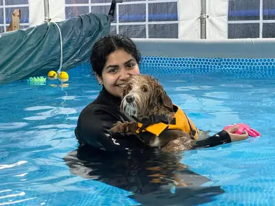 a woman in a swimming pool holding a dog at Charming Retreat with Sauna, Dog Swimming Pool, and Rural Charm in Leyland