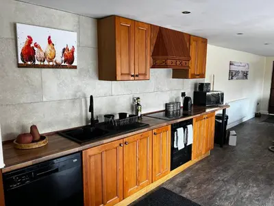 a kitchen with wooden cabinets and chickens on the wall at Charming Retreat with Sauna, Dog Swimming Pool, and Rural Charm in Leyland