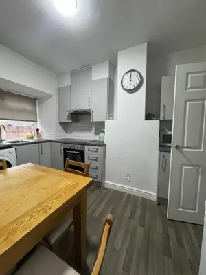 a kitchen with a wooden table and a clock on the wall at Hillside Stays - Cosy 2 Bed Bungalow, Pet Friendly in Blackpool