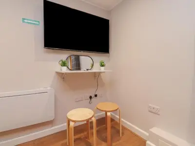 a room with two stools and a tv on the wall at Morcombe Retreat in Morecambe