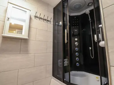 a bathroom with a shower with a sink and a mirror at Morcombe Retreat in Morecambe