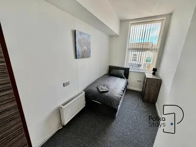 a room with a couch in the corner of a room at Comfy Ormskirk Family Stay by PolkaStays in Ormskirk