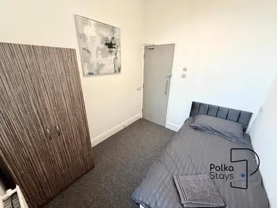 a bedroom with a bed and a wooden cabinet at Comfy Ormskirk Family Stay by PolkaStays in Ormskirk