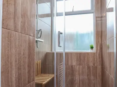 a shower with a glass door and a window at West End Retreat in Morecambe