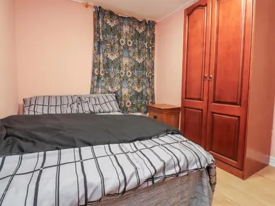 a bedroom with a bed and a wooden cabinet at West End Retreat in Morecambe