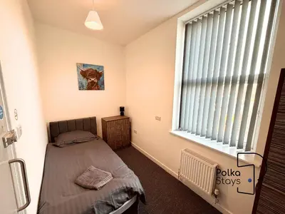 a bedroom with a bed and a window with blinds at Spacious Ormskirk Contractor Stay by PolkaStays in Ormskirk