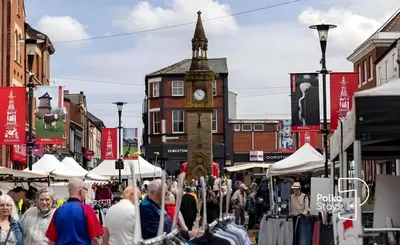 a crowd of people walking down a street with a clock tower at Spacious Ormskirk Contractor Stay by PolkaStays in Ormskirk