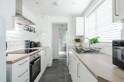 a kitchen with white cabinets and a counter top at Cosy Anfield Home in Liverpool