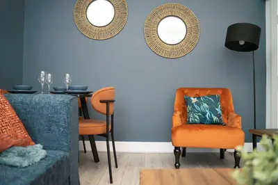 a living room with an orange chair and a table at Cosy Anfield Home in Liverpool