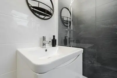 a bathroom with a white sink and a mirror at Cosy Anfield Home in Liverpool