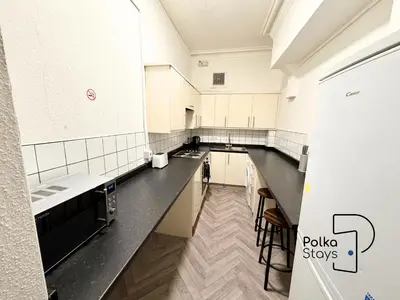 a kitchen with white cabinets and black counter tops at Sleeps 10 Spacious for Contractors by PolkaStay in Ormskirk