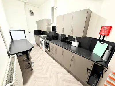 a kitchen with white cabinets and a black counter top at Sleeps 10 Spacious for Contractors by PolkaStay in Ormskirk