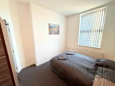 a bedroom with a bed and a window at Sleeps 10 Spacious for Contractors by PolkaStay in Ormskirk
