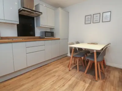 a kitchen with white cabinets and a table and chairs at Seaside Serenity in Lytham St Annes
