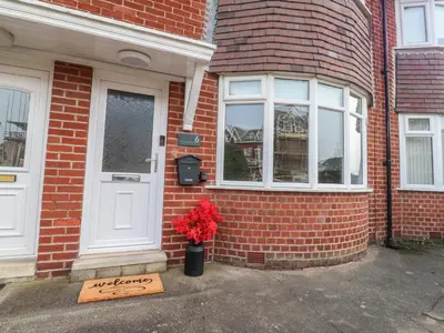 a sign in front of a brick house with a vase of flowers at Seaside Serenity in Lytham St Annes