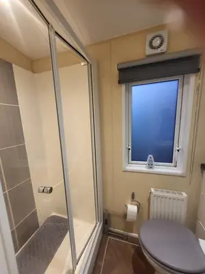 a bathroom with a shower and a toilet and a window at 47 Venture Caravan Park in Morecambe