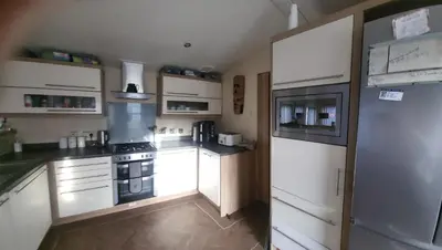 a small kitchen with white cabinets and a refrigerator at 47 Venture Caravan Park in Morecambe