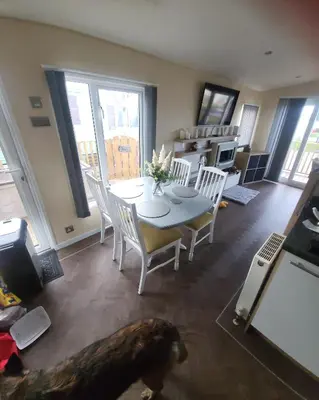 a dog standing in a living room with a table and chairs at 47 Venture Caravan Park in Morecambe