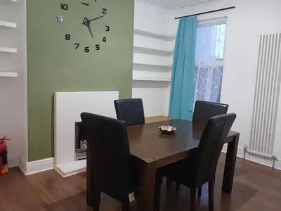 a dining room with a table and chairs and a clock at Anfield Breaktime House in Liverpool