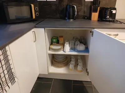 a cupboard with plates and dishes in a kitchen at Anfield Breaktime House in Liverpool