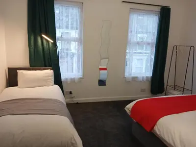 two beds in a room with two windows at Anfield Breaktime House in Liverpool