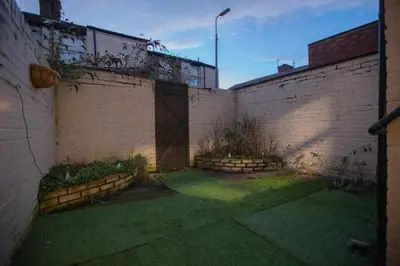 an alley with a brick wall with a gate at Cozy Liverpool Base Close to City Centre in Liverpool