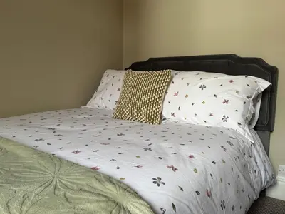 a bed with a white comforter with flowers on it at Homely 3 bedroom House in Liverpool in Liverpool