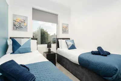 two beds in a room with a window at Spacious 3BR Sleeps 8 Ideal for Contractors or Large groups in Liverpool