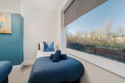 a bedroom with a bed with blue sheets and a window at Spacious 3BR Sleeps 8 Ideal for Contractors or Large groups in Liverpool
