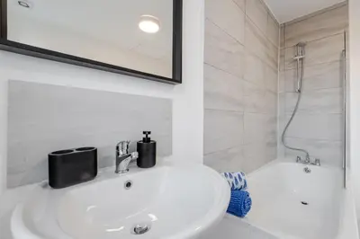 a white bathroom with a sink and a shower at Spacious 3BR Sleeps 8 Ideal for Contractors or Large groups in Liverpool