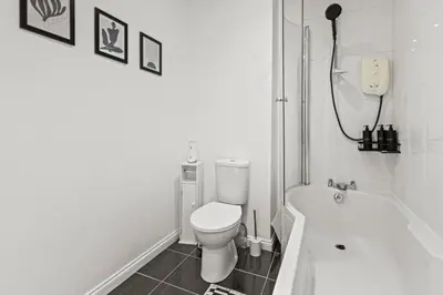 a white bathroom with a toilet and a bath tub at Spacious 2 Bed Apartment With Secure Free Parking in Liverpool