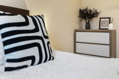 a bed with a black and white pillow and a nightstand at Spacious 2 Bed Apartment With Secure Free Parking in Liverpool