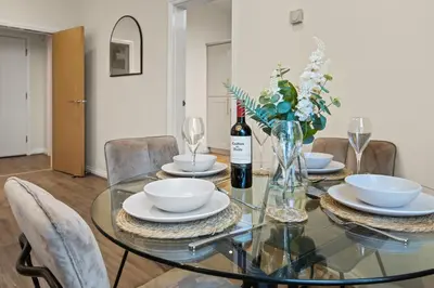 a glass table with a vase of flowers and a bottle of wine at Spacious 2 Bed Apartment With Secure Free Parking in Liverpool