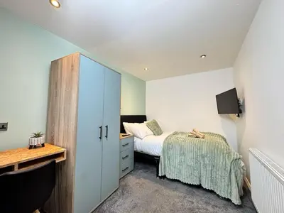 a bedroom with a bed and a desk and a cabinet at Sleeps 12 TV in Every Room 6 Bedrooms in Liverpool