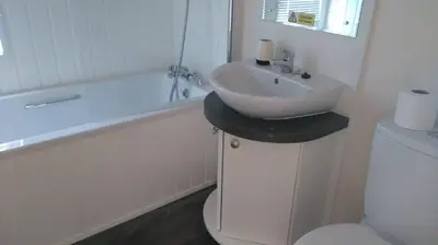 a white bathroom with a sink and a tub and a toilet at Shrimp Shack in Heysham