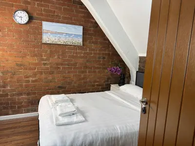 a bedroom with a brick wall with a bed and a clock at Prime City Apt with Parking - Steps to Bars & Trains in Liverpool