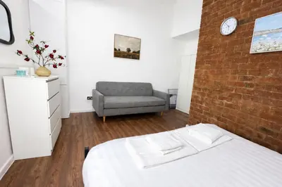 a bedroom with a brick wall and a bed and a chair at Prime City Apt with Parking - Steps to Bars & Trains in Liverpool
