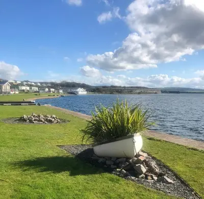 a plant in a pot on the grass near the water at Lisas Lodge in the Lake District in Millom