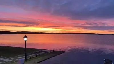 a sunset over a body of water with a street light at Lisas Lodge in the Lake District in Millom