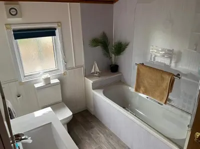 a bathroom with a tub and a toilet and a sink at Lisas Lodge in the Lake District in Millom