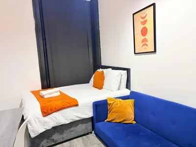 a bed with a blue couch in a room at 12A Charming Double Room in shared home at Pembroke in Liverpool