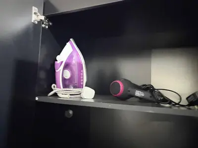 a shelf with a pink iron and a hair dryer at 12A Charming Double Room in shared home at Pembroke in Liverpool