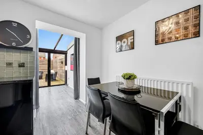 a dining room with a table and chairs and a clock at Cemeas House - Air Host & Stay - Slps 6 - Parking in Liverpool