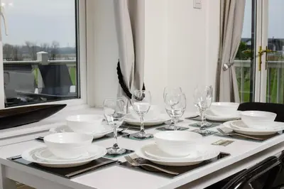 a table with plates and wine glasses on it at Tranquil Lodge with river views in Hambleton